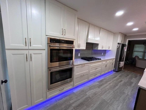 Remodeled galley kitchen in Richardson, TX with white cabinets and modern lighting